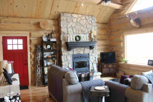 Stone fireplace and living area with log walls