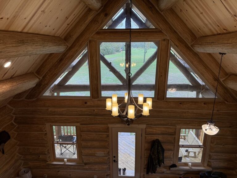 Great room window wall framed by heavy log trusses