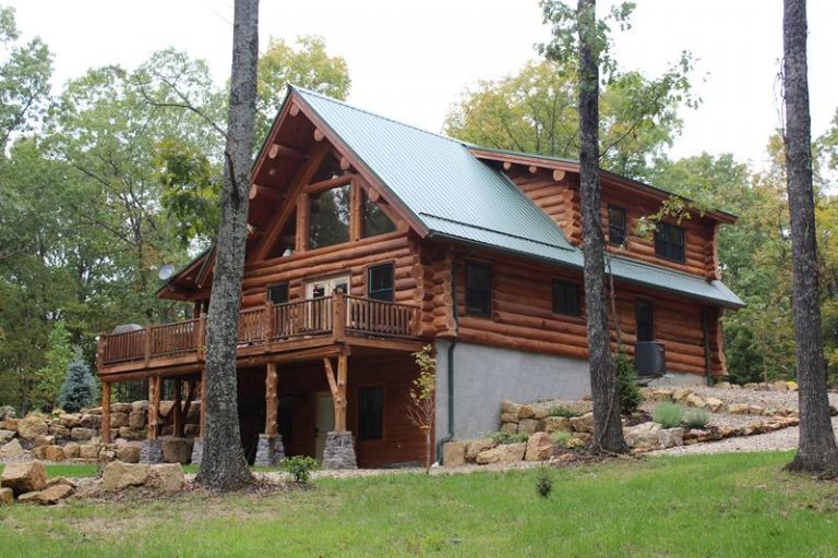The Kelley log home standing in the trees with dormers and a metal roof